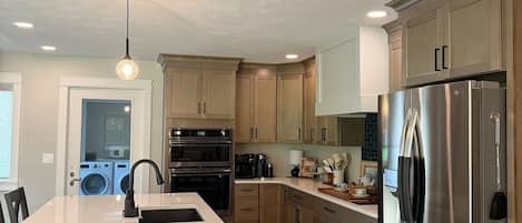 A modern kitchen with a central island, stainless steel appliances, and wooden cabinetry.