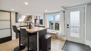 A modern kitchen with a central island, bar stools, and a view of the outside. - A Little piece of Paradise - stunning ocean views! (Lunenburg)