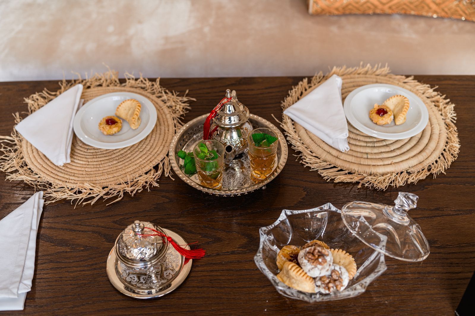 A table set with plates of food, glasses of tea, and decorative items.