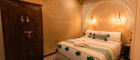 A room with a bed, a wooden wardrobe, and a decorative wall.