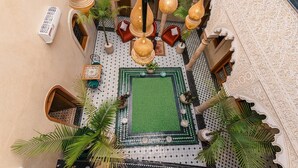 Un patio interior con lámparas colgantes, zonas de estar y un suelo con diseños.