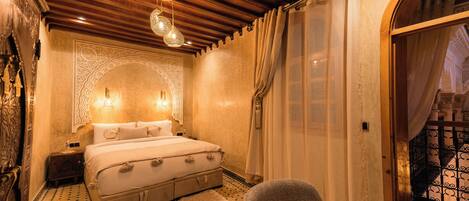 A bedroom with a bed, a nightstand, a chair, and a decorative wall.