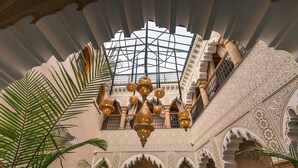 An ornate interior with a high ceiling, intricate wall designs, and a central chandelier. - Golden Riad (Rabat)
