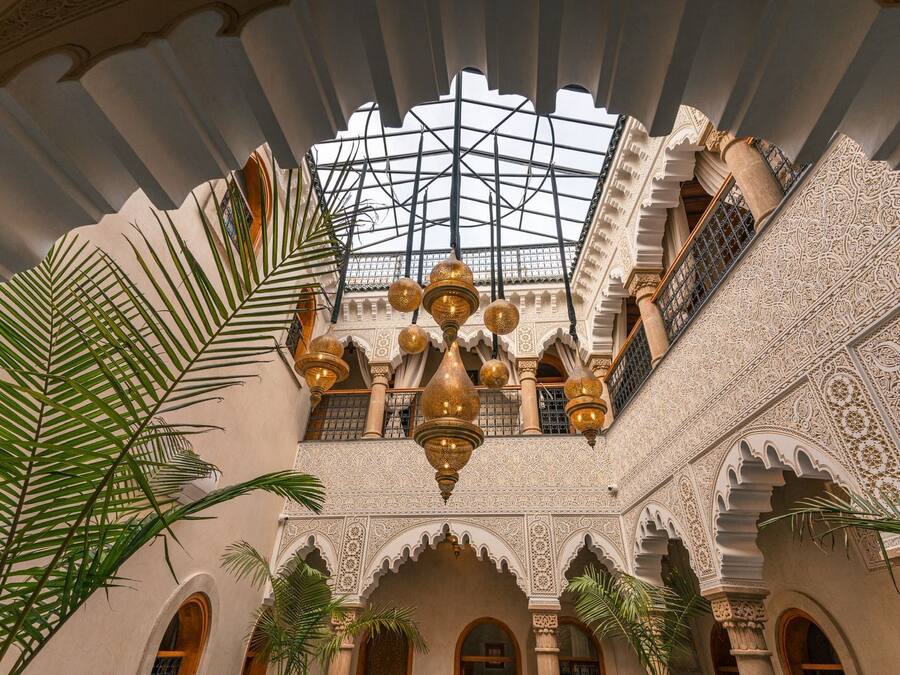 Un interior ornamentado con techo alto, diseños intrincados en las paredes y una lámpara central.
