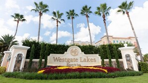 Schild für Westgate Lakes Resort & Spa mit angelegter Bepflanzung im Vordergrund und Palmen.