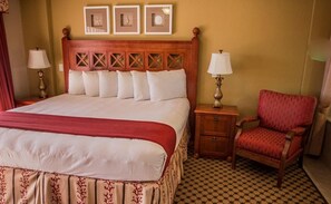 A hotel room with a large bed, a wooden headboard, a nightstand, a red armchair, and a checkered floor. - Studio Near Disney & Universal - Westgate Lakes Resort (Orlando)