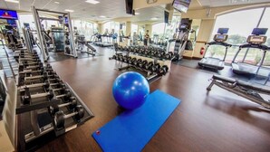 Ein Fitnessraum mit Trainingsgeräten, einer blauen Yogamatte und einem großen, blauen Trainingsball.
