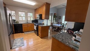 Una cocina con armarios de madera, microondas y comedor con mesa y sillas.