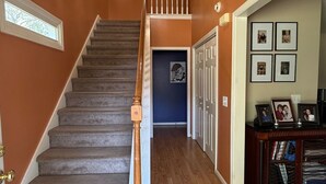 Una escalera con barandilla de madera que lleva a un rellano con candelabro.
