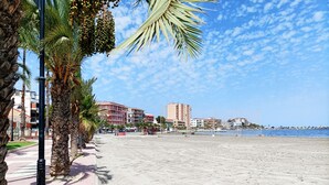 A beach with palm trees, a clear sky, and buildings in the background. - Stylish Apartment in Central Location (San Pedro del Pinatar)