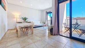 A spacious room with a dining area, a sofa, and a balcony with a table and chairs. - Stylish Apartment in Central Location (San Pedro del Pinatar)