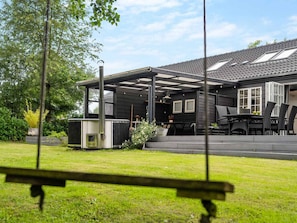 A house with a covered patio, a hot tub, and a lawn. - 4 Star Holiday Home in Vig (Vig)