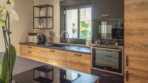Une cuisine moderne équipée d’un four encastré, d’un évier et d’une fenêtre.