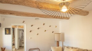 Un salon chaleureux avec un plafond en bois, un fauteuil en osier, un canapé avec des coussins, une lampe et des autocollants décoratifs représentant des papillons sur les murs.