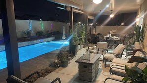 A poolside area with a stone patio, lounge chairs, and potted plants. - Fabulous 6-bedroom townhome with AC in sunny Indio (Indio)