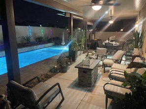Ein Poolbereich mit Steinpflasterung, Liegestühlen und Kübelpflanzen.