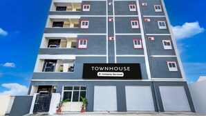 Monikerroksinen rakennus, jonka kyltissä lukee: ”TOWNHOUSE – tarjoamme täyden palvelun”.