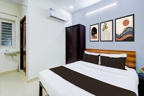 Ein Hotelzimmer mit Bett, Schrank, Klimaanlage, einem Kunstwerk an der Wand und einem Fenster mit Jalousien.