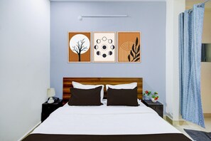 Ein Schlafzimmer mit einem hölzernen Kopfteil, einem Bett mit weißer und brauner Bettwäsche, einem Nachttisch mit einer Lampe und einer Wand mit drei gerahmten Kunstwerken.