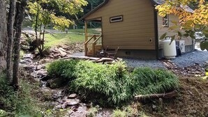 Una casa con un porche cubierto, un pequeño espacio para sentarse al aire libre y una fuente de agua.