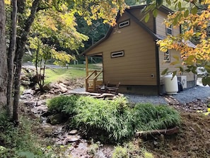 A house with a covered porch, a small outdoor seating area, and a water feature. - Cozy Creekside Cabin in Bryson City, North Carolina (Bryson City)