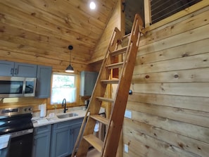 A wooden interior with a kitchen area, including cabinets, a microwave, and a stove. - Cozy Creekside Cabin in Bryson City, North Carolina (Bryson City)
