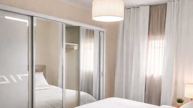 Ein modernes Schlafzimmer mit einem großen Bett, einem Kleiderschrank mit Spiegeln und einer Pendelleuchte.
