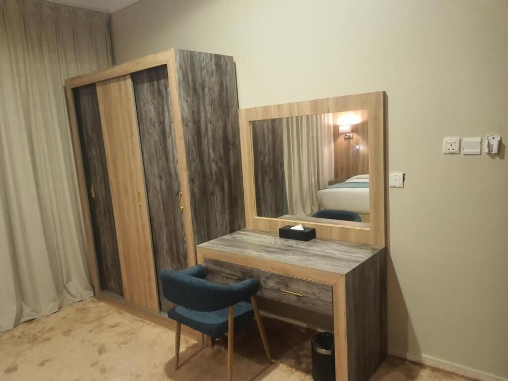 A room with a wooden desk, a chair, a mirror, and a wardrobe.