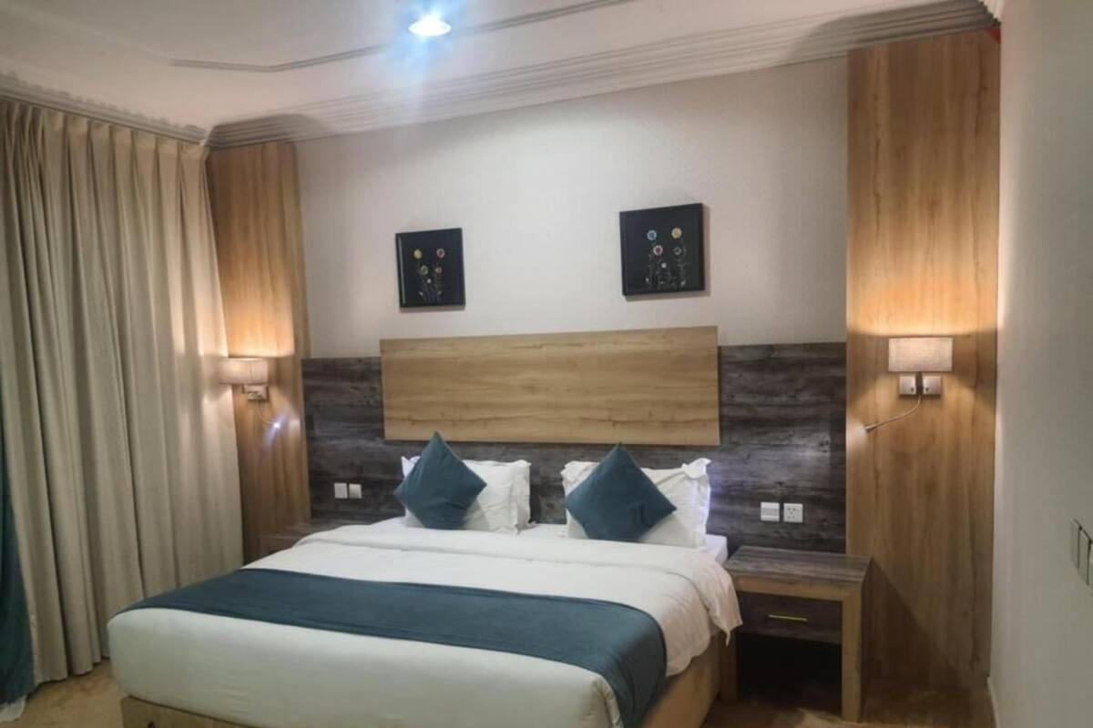 Una camera d'albergo con un letto, comodini, quadri alle pareti e tende.
