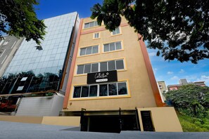 Um edifício de vários andares com fachada de vidro, um letreiro indicando 'Collection Company Services' e uma entrada com portão.