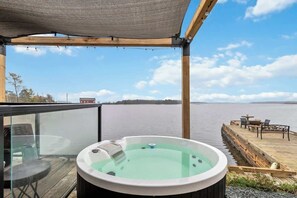A hot tub on a wooden deck with a view of a lake. - Book 2 homes together. Ocean Views. Sleeps 8! (Lunenburg)