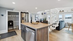 A modern kitchen with a central island, stainless steel appliances, and a staircase leading to a loft area. - Book 2 homes together. Ocean Views. Sleeps 8! (Lunenburg)