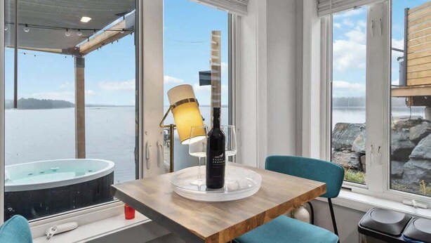 A room with a wooden table, a glass-topped coffee table, a bottle of wine, and a lamp. - Book 2 homes together. Ocean Views. Sleeps 8! (Lunenburg)