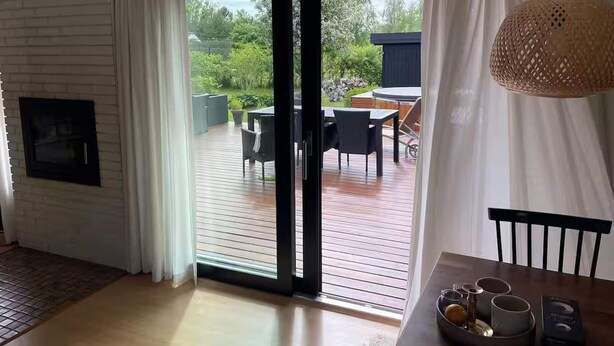 Una habitación con puerta corrediza de vidrio que da a una terraza exterior con mesa y sillas.