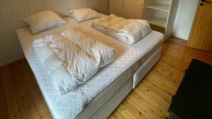 Un dormitorio con cama, almohadas, armario y una lámpara en el techo.