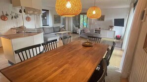Una cocina moderna con una mesa de comedor de madera, luces colgantes y vista al área de estar.