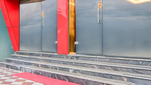 A building entrance with a red and grey facade, a push button, and a set of stairs leading up to the entrance. - Super Townhouse Aiims Kolkata (Kalyani)