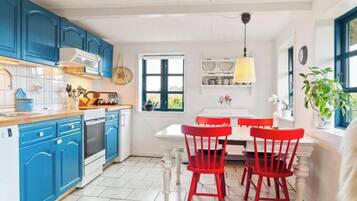 Cozinha com armários azuis, bancada branca e conjunto de jantar vermelho.