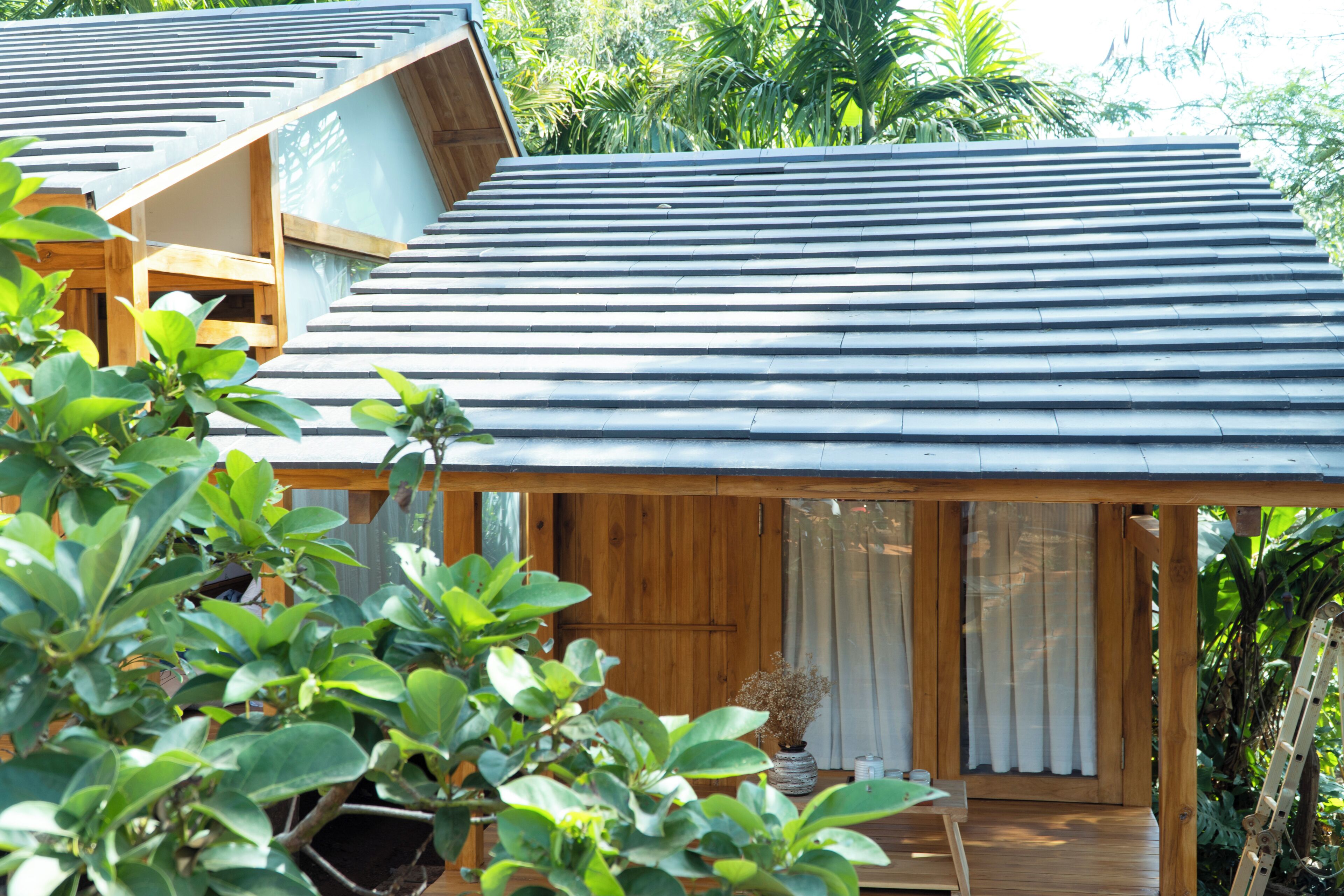 A wooden cabin with a sloped roof, a small porch, and a window with curtains.