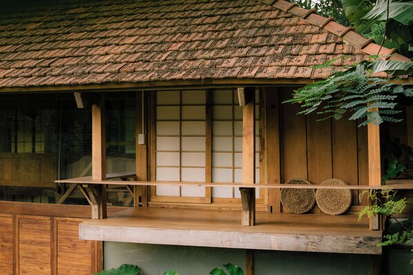 A traditional wooden building with a tiled roof, wooden beams, and a window with a grid pattern.