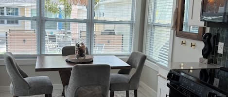 A modern kitchen with a dining area, large windows, and a chandelier.
