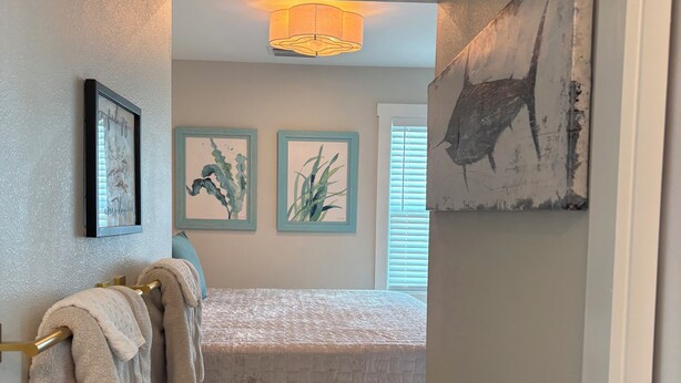 Un dormitorio con cama, toallero, alfombra y decoración en la pared.