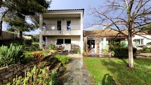 Ein zweistöckiges Haus mit Balkon, einem Steinweg und einem Garten mit verschiedenen Pflanzen.