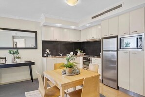 A modern kitchen with a dining area, stainless steel appliances, and a large mirror. - Sleeps 4 People - City Centre - 100m to Casino (Brisbane City)