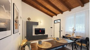 A modern living room with a TV, dining table, and chairs.