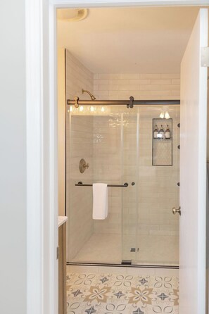 Eine begehbare Dusche mit Glaswänden, einem Handtuchhalter und einem gerahmten Bild an der Wand.