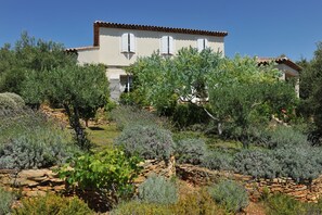 A two-story house with a stone wall and a garden with various plants. - Entre mer et garrigue - Charming house with pool and sea view in Provence (LA CADIERE D'AZUR)
