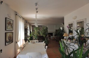A spacious living room with a dining area, a fireplace, and various plants. - Entre mer et garrigue - Charming house with pool and sea view in Provence (LA CADIERE D'AZUR)