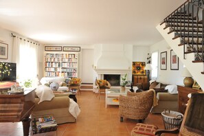 A living room with a fireplace, bookshelves, and a staircase. - Entre mer et garrigue - Charming house with pool and sea view in Provence (LA CADIERE D'AZUR)