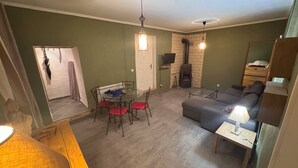 Una sala de estar con un sofá, una mesa de comedor de vidrio y sillas, una chimenea y un televisor.